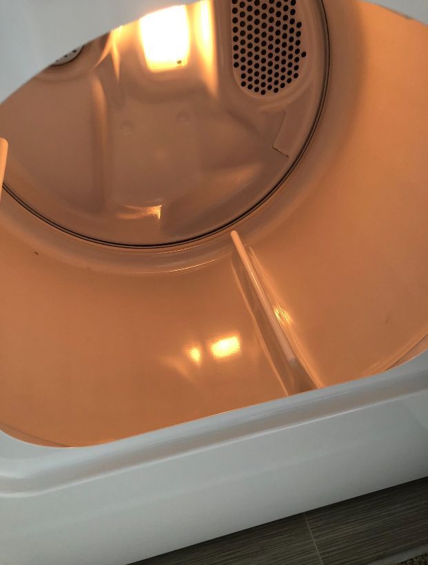 The inside of a white dryer with a light on