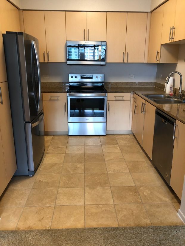 A kitchen with stainless steel appliances and tan cabinets