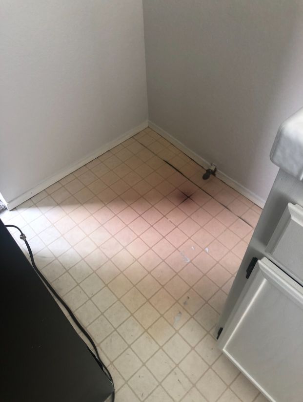 A kitchen with a dirty tile floor and a stove