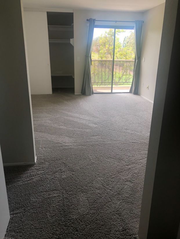 A living room with a sliding glass door and a balcony.