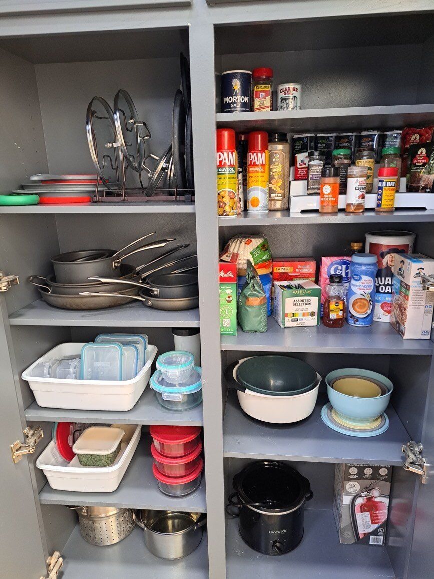 A pantry filled with pots , pans , bowls , and bottles.