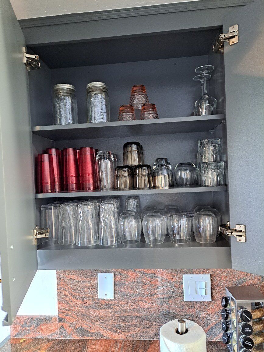 A kitchen cabinet filled with lots of glasses and jars.