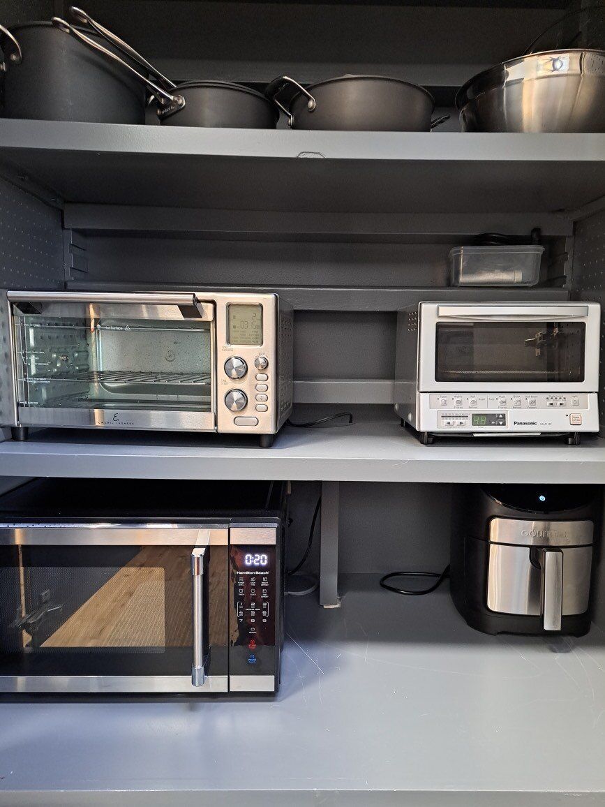 A microwave oven and toaster oven are on a shelf