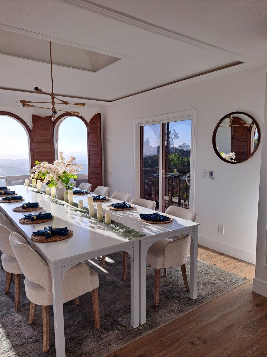 A dining room with a long table and chairs and a mirror.