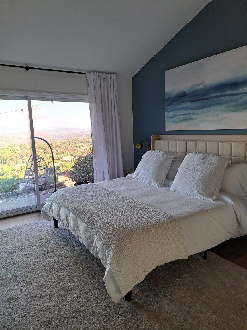 A bedroom with a large bed and a painting on the wall.