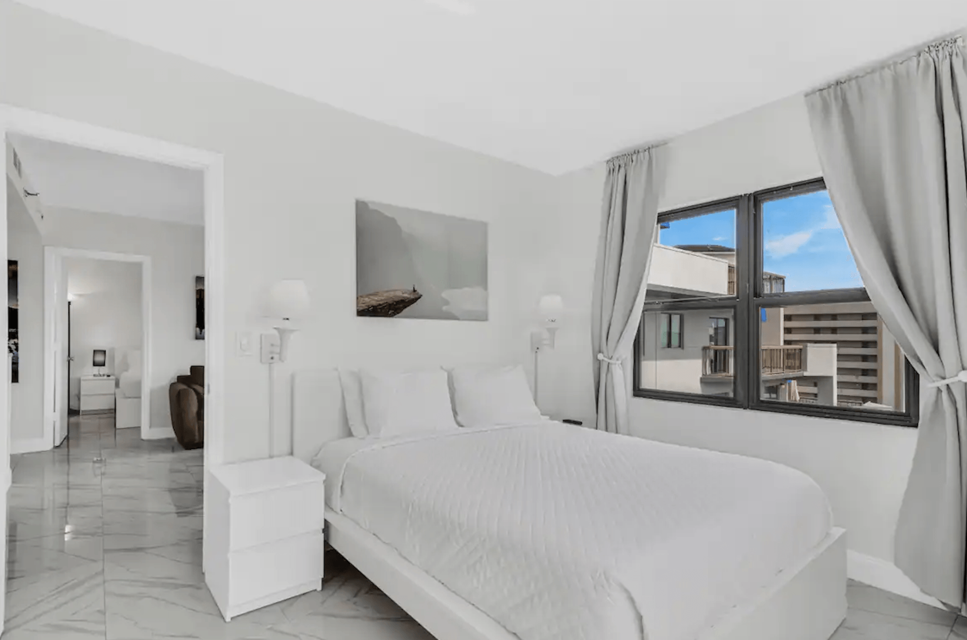 A bedroom with a bed , nightstand , and two windows.