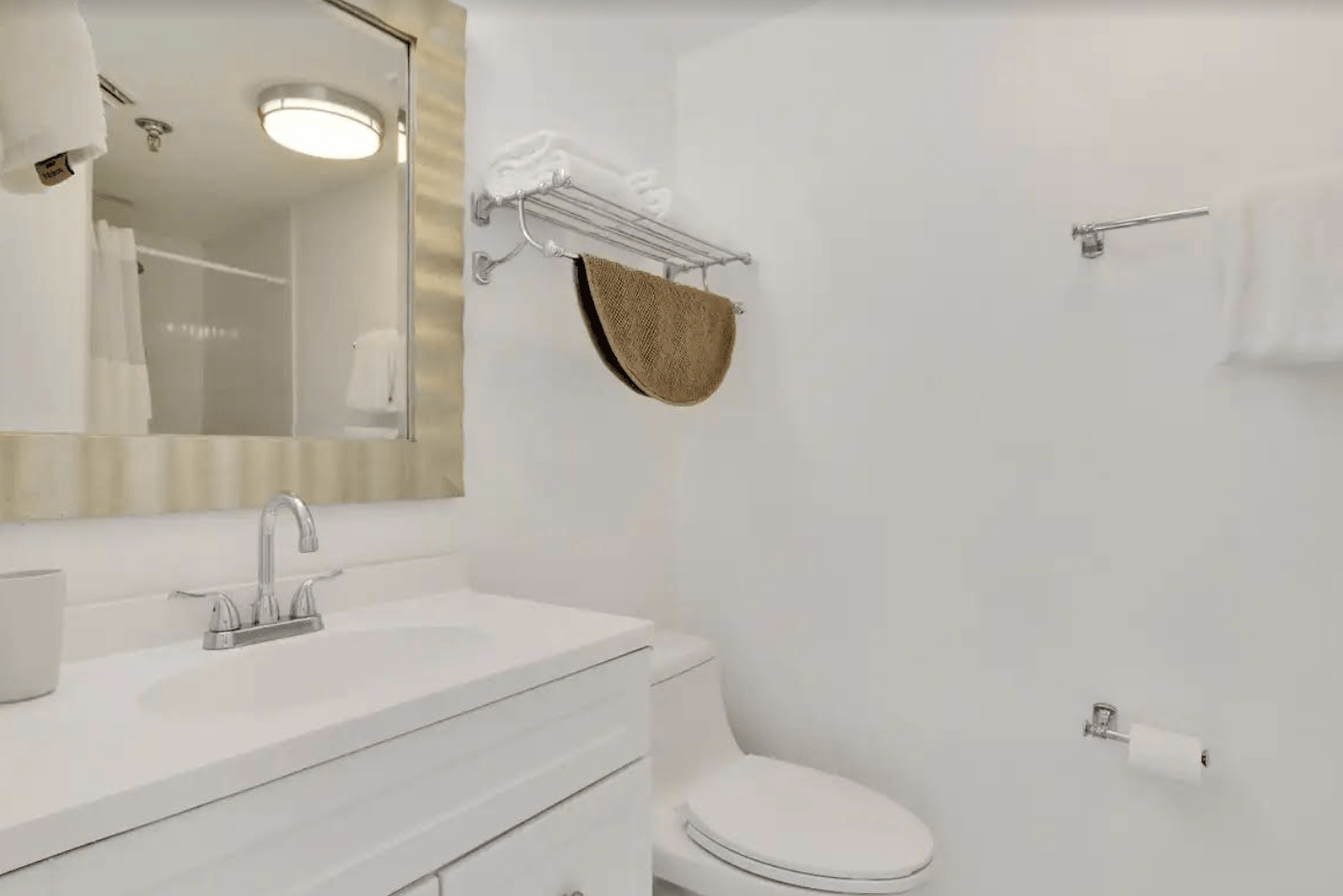 A bathroom with a sink , toilet , mirror and towel rack.