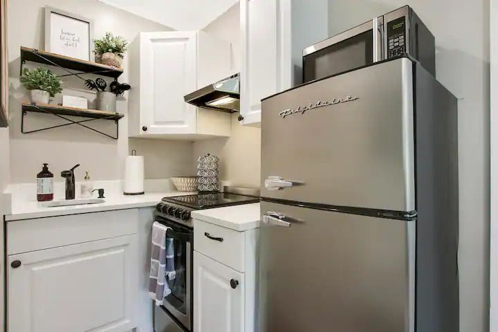 A kitchen with a refrigerator , microwave , stove and sink.
