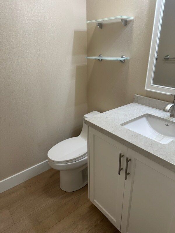 A bathroom with a toilet , sink and mirror.