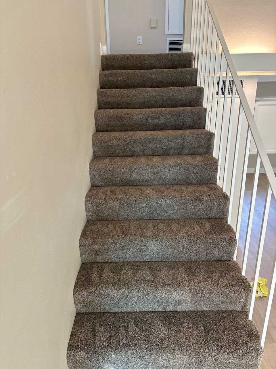 A staircase with a carpeted staircase and a railing in a house.