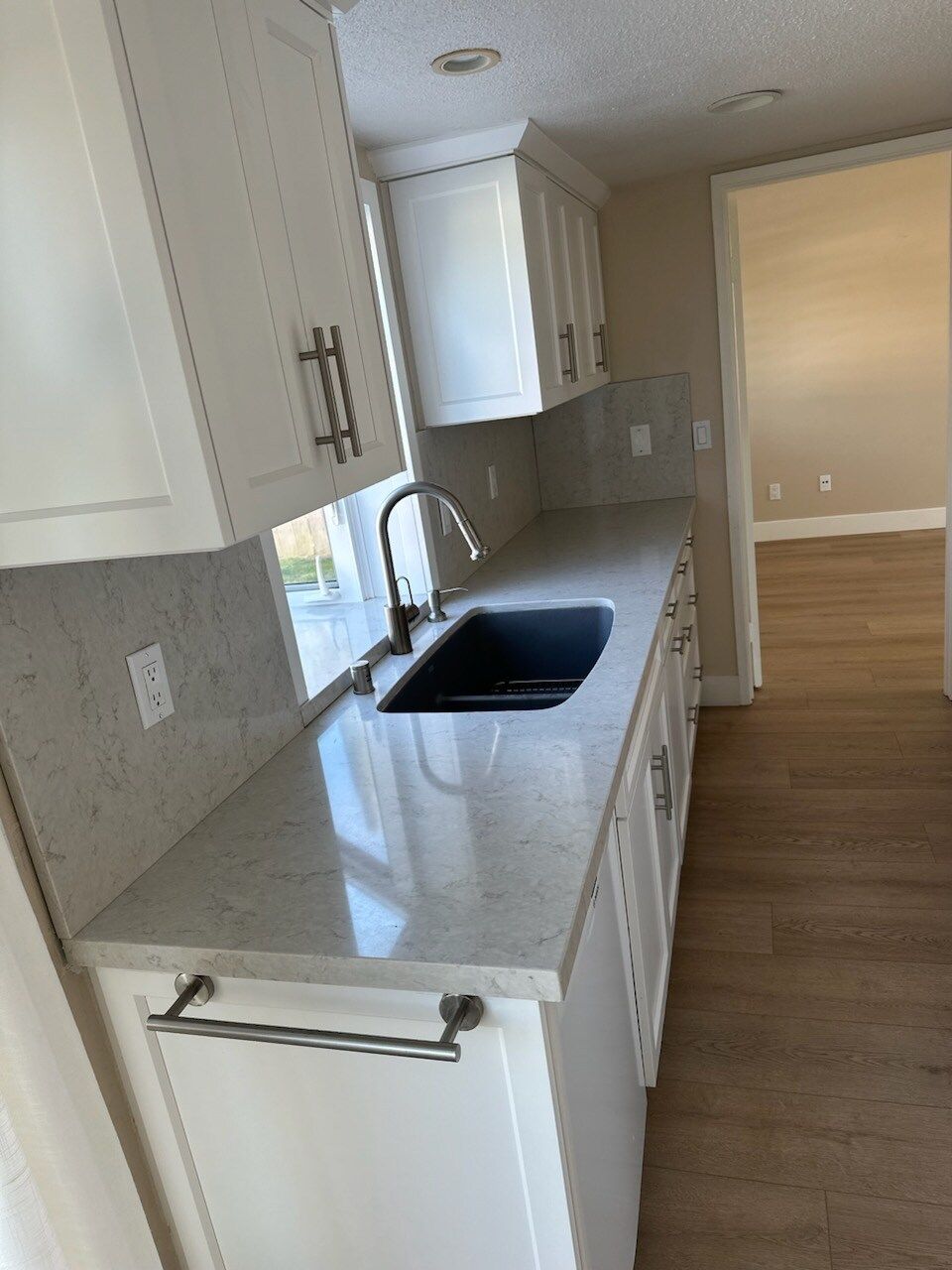 A kitchen with white cabinets and a sink.