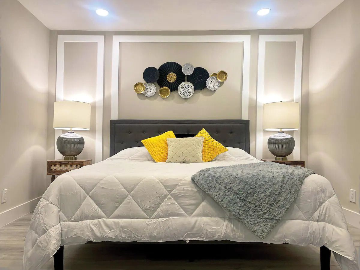 A bedroom with a bed , lamps and a wall decoration.