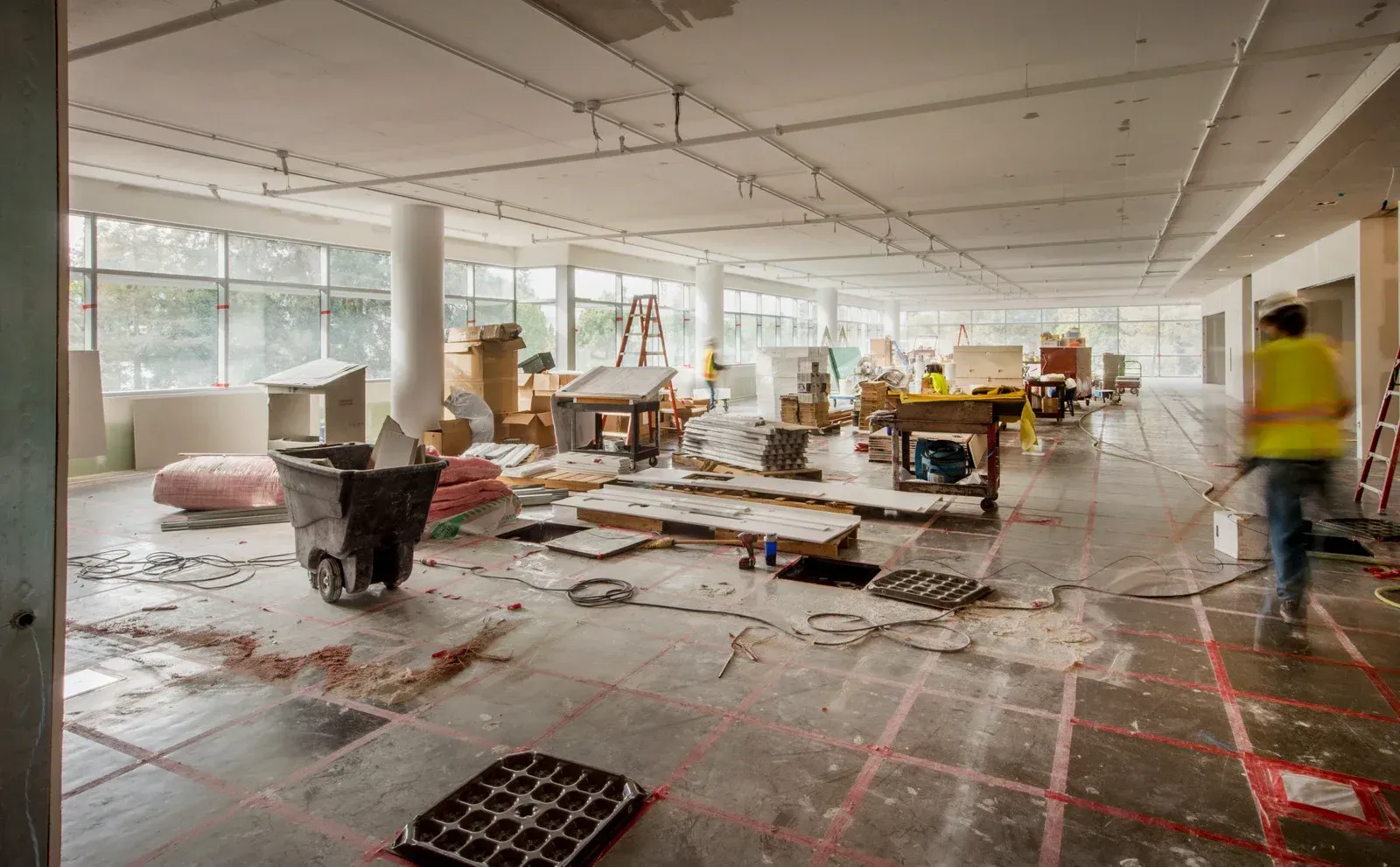 A large room is being remodeled and a man is walking through it.