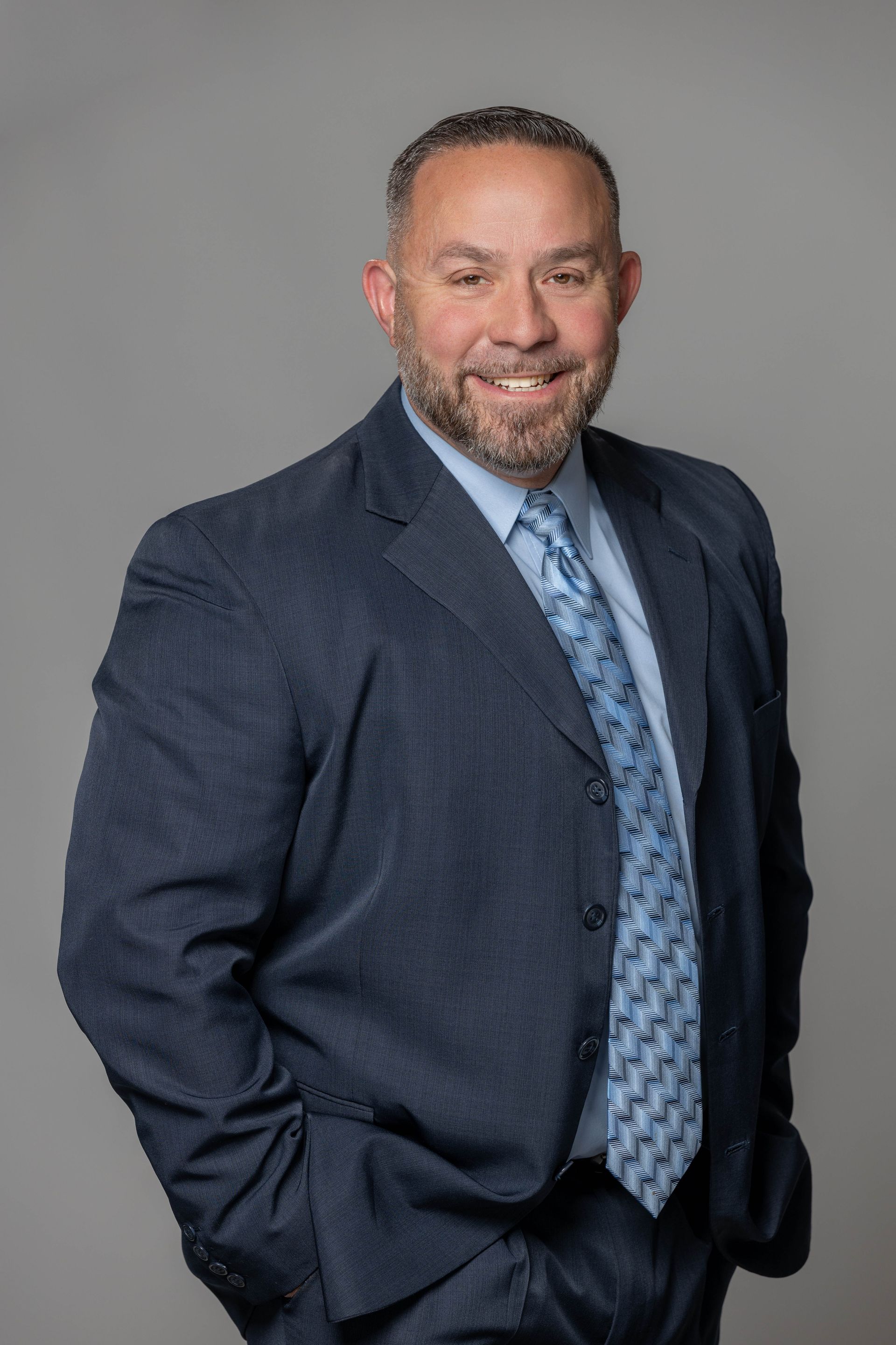 A man in a suit and tie is standing with his hands in his pockets.
