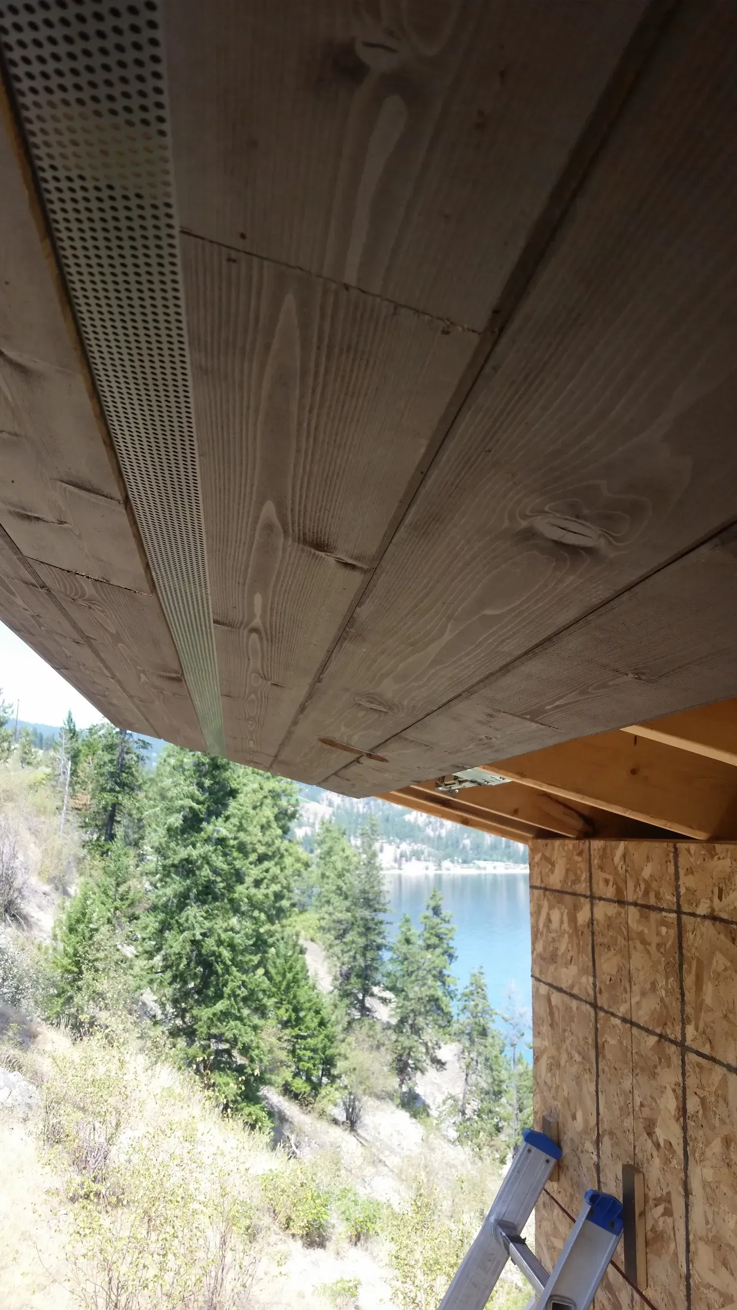 A ladder is leaning against a wall next to a wooden ceiling.