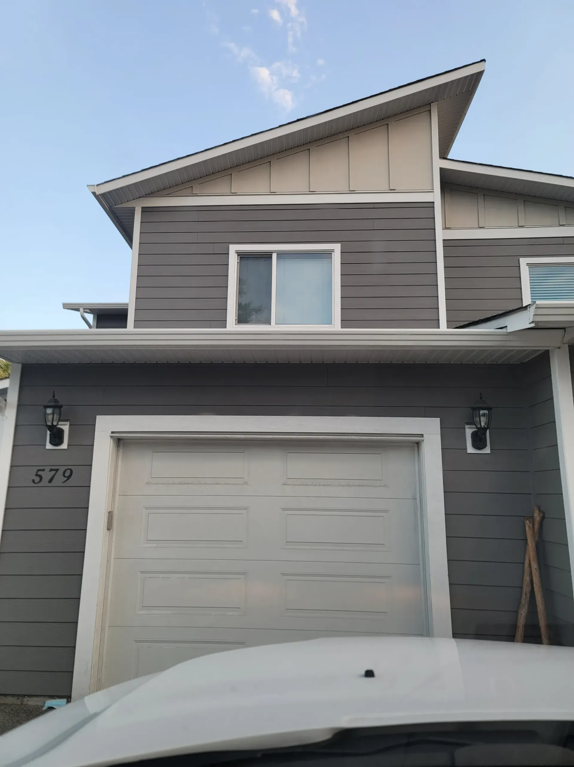 A car is parked in front of a house with a garage door