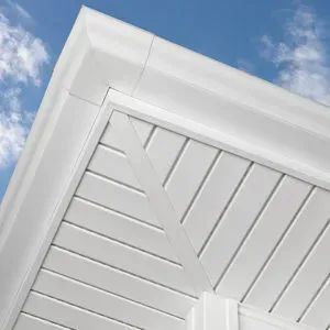 A close up of a white soffit on a house with a blue sky in the background.