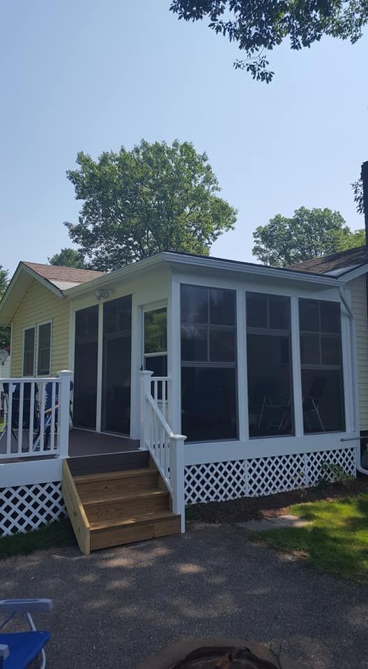 Yellow house with screen porch and wooden deck; white railing and stairs.