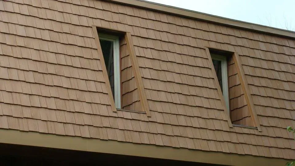 Brown shingle roof with two triangular dormer windows.