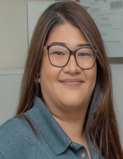 Woman wearing glasses smiles at the camera in a gray shirt.