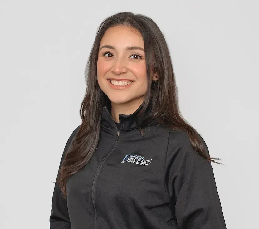 Smiling woman with long dark hair, wearing a black zip-up jacket against a white background.