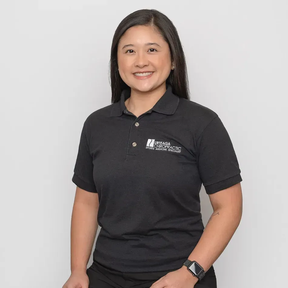 Woman with dark hair wearing a black polo shirt smiles, against a white background.