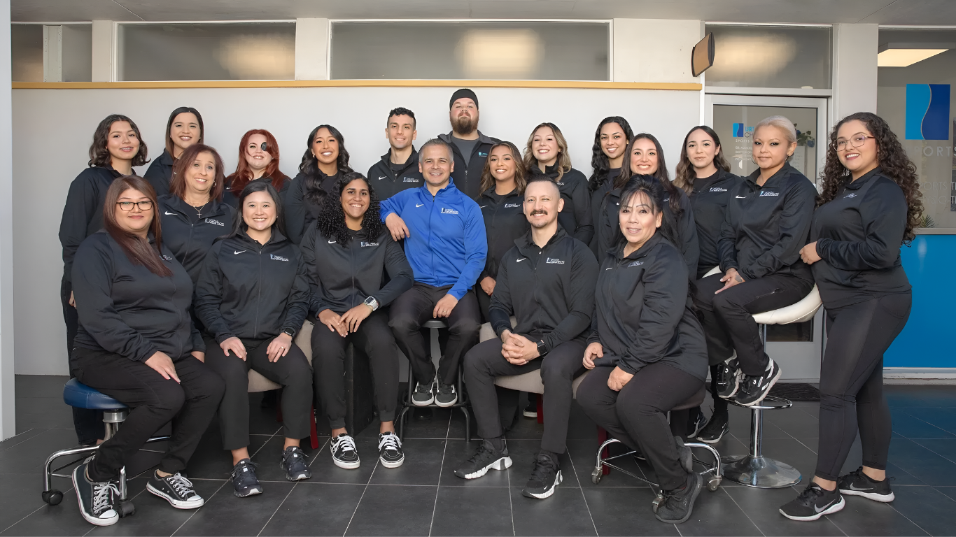 A group photo of a medical team in black jackets, posing indoors, smiling.