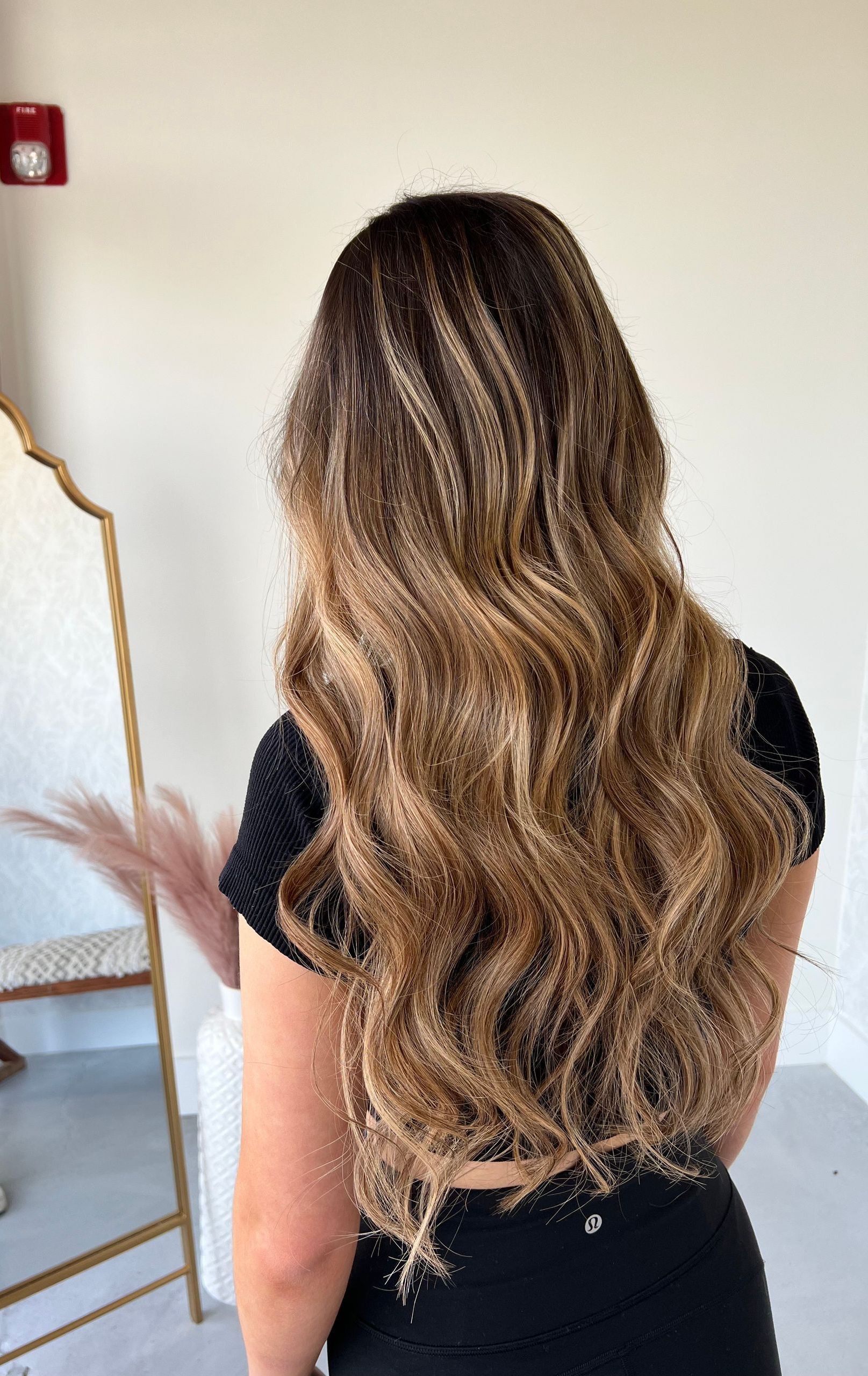 A woman with long brown hair is standing in front of a mirror.