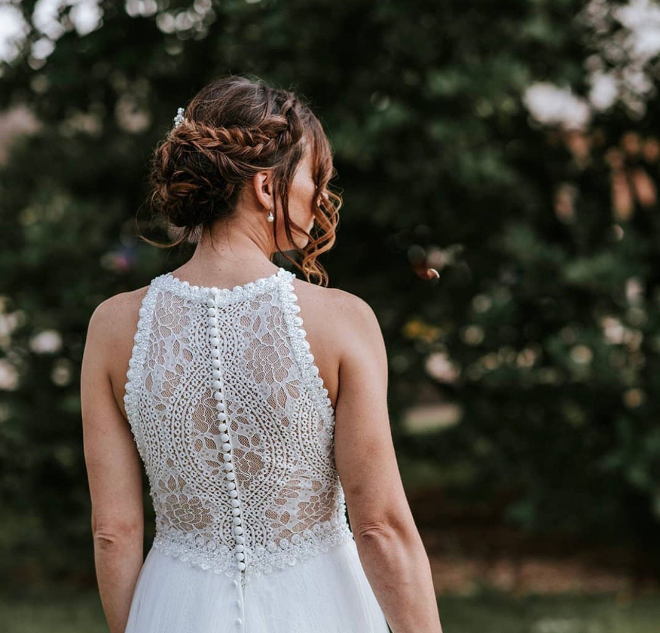 The back of a woman in a wedding dress is shown.