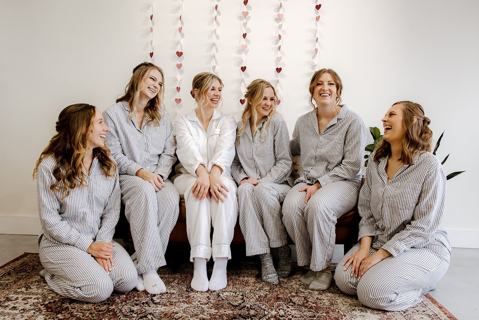 A group of women in pajamas are sitting next to each other on a rug.