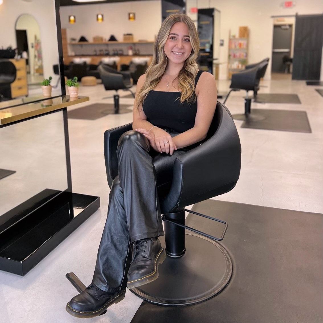A woman is sitting in a black chair in a salon