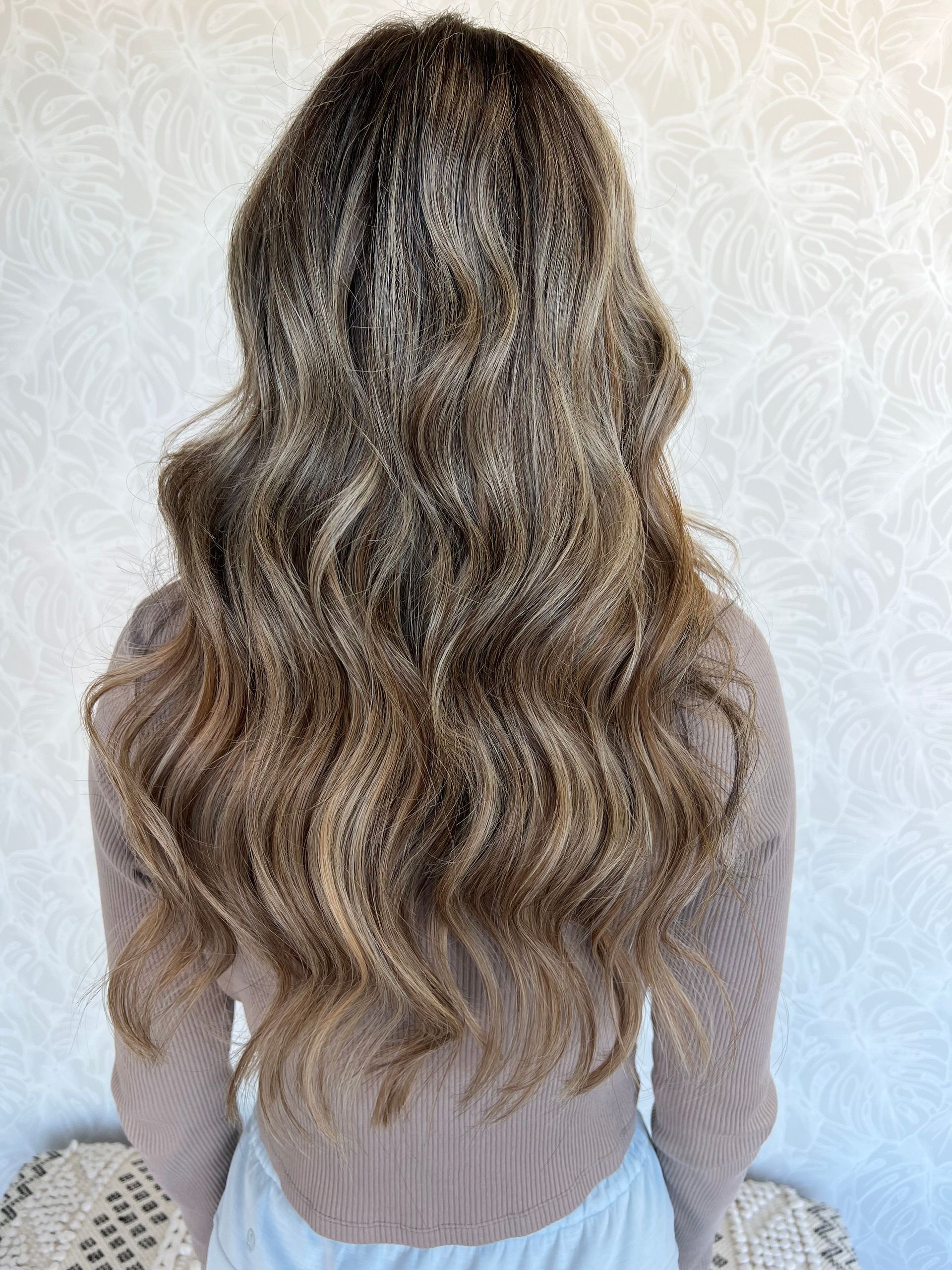 The back of a woman 's head with long wavy hair.