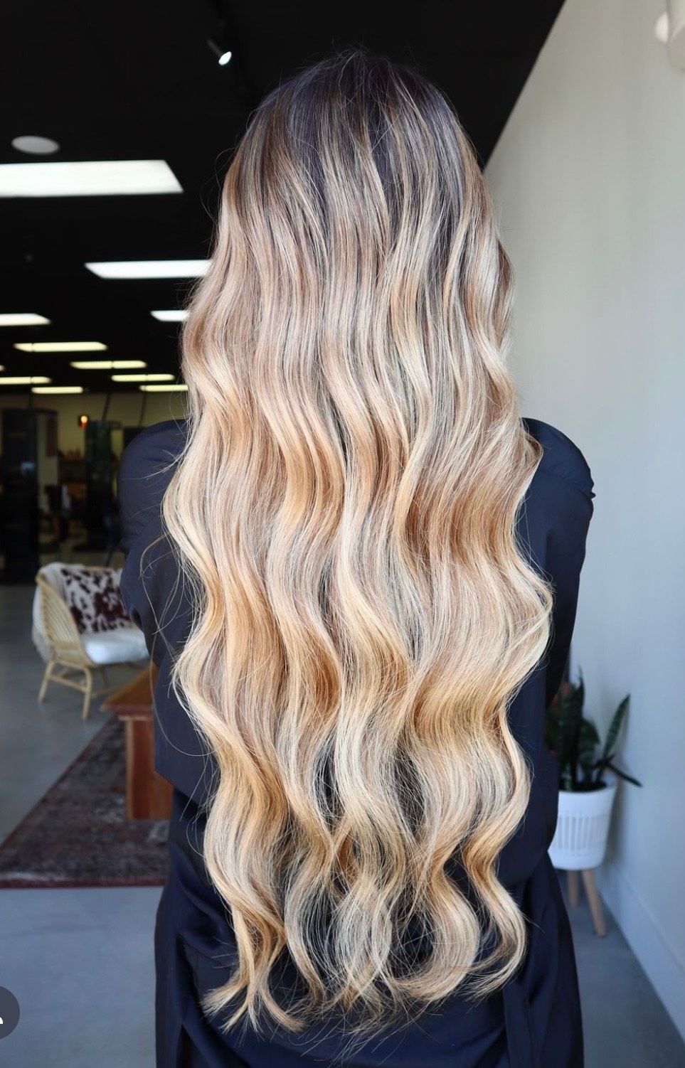 A woman with long wavy blonde hair is standing in a room.