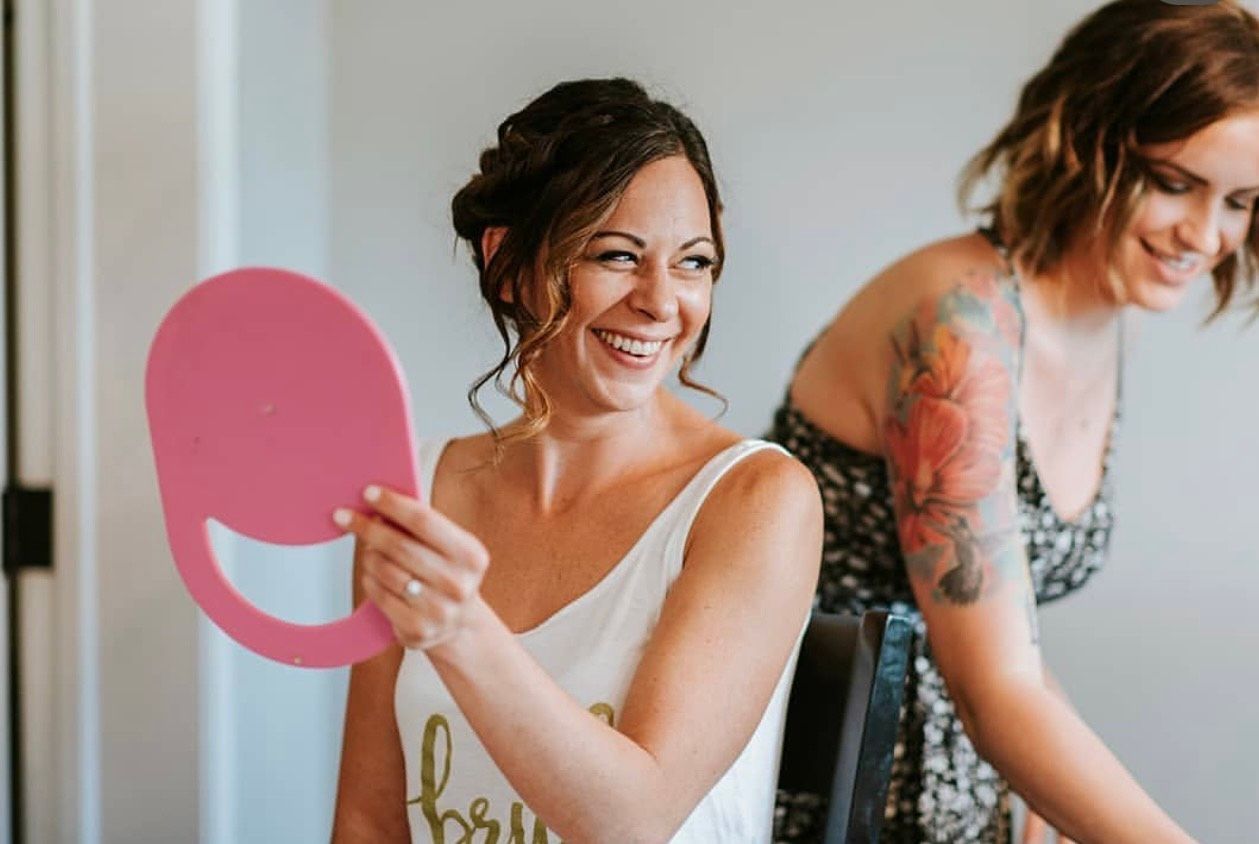 A bride is smiling while looking at herself in a mirror.