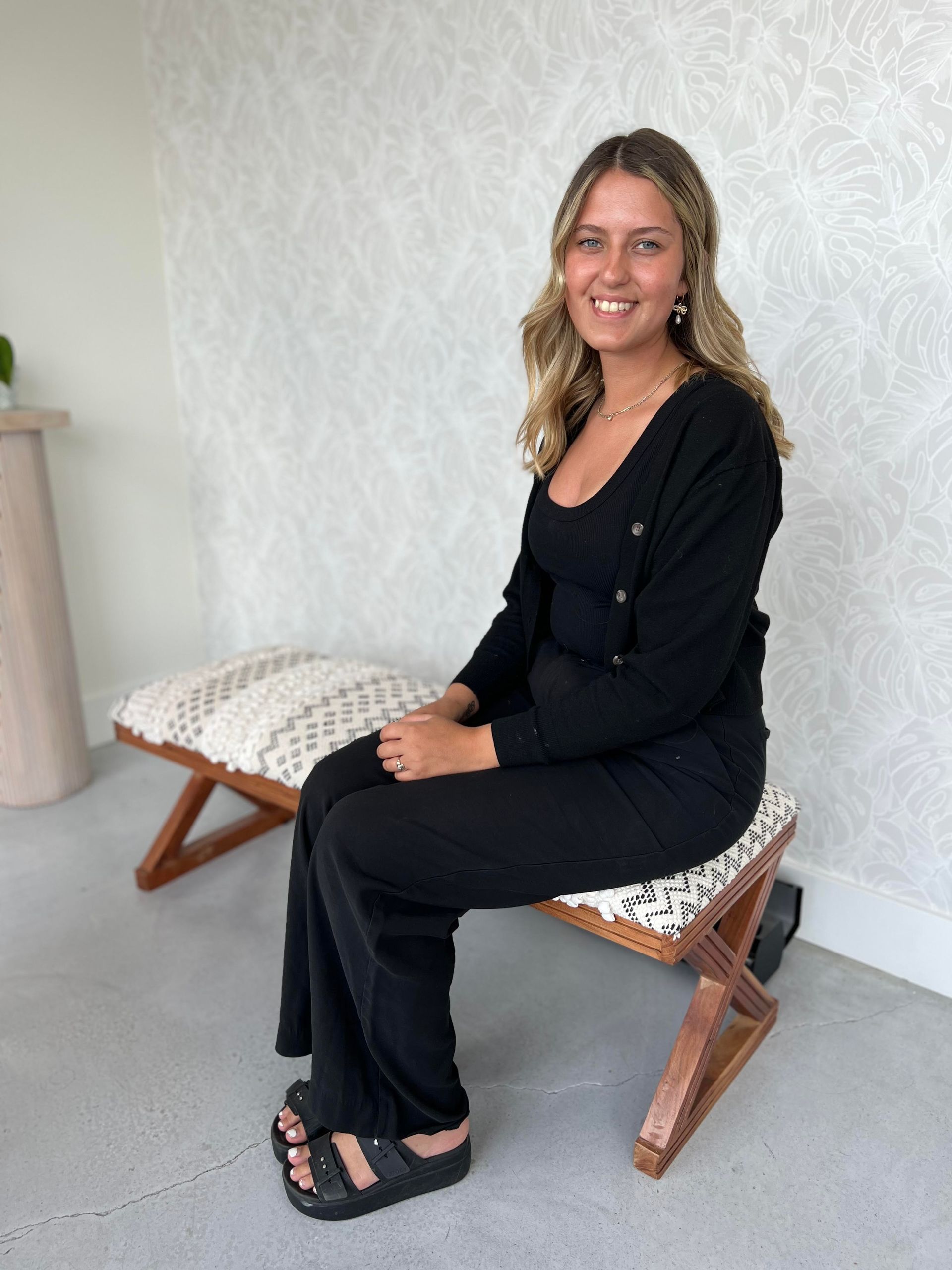 A woman is sitting on a wooden bench and smiling.