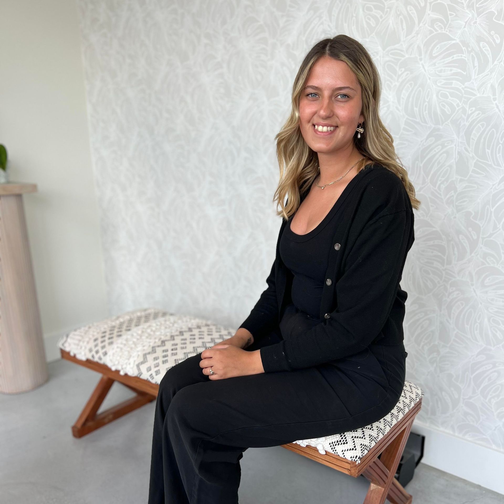A woman is sitting on a wooden bench and smiling