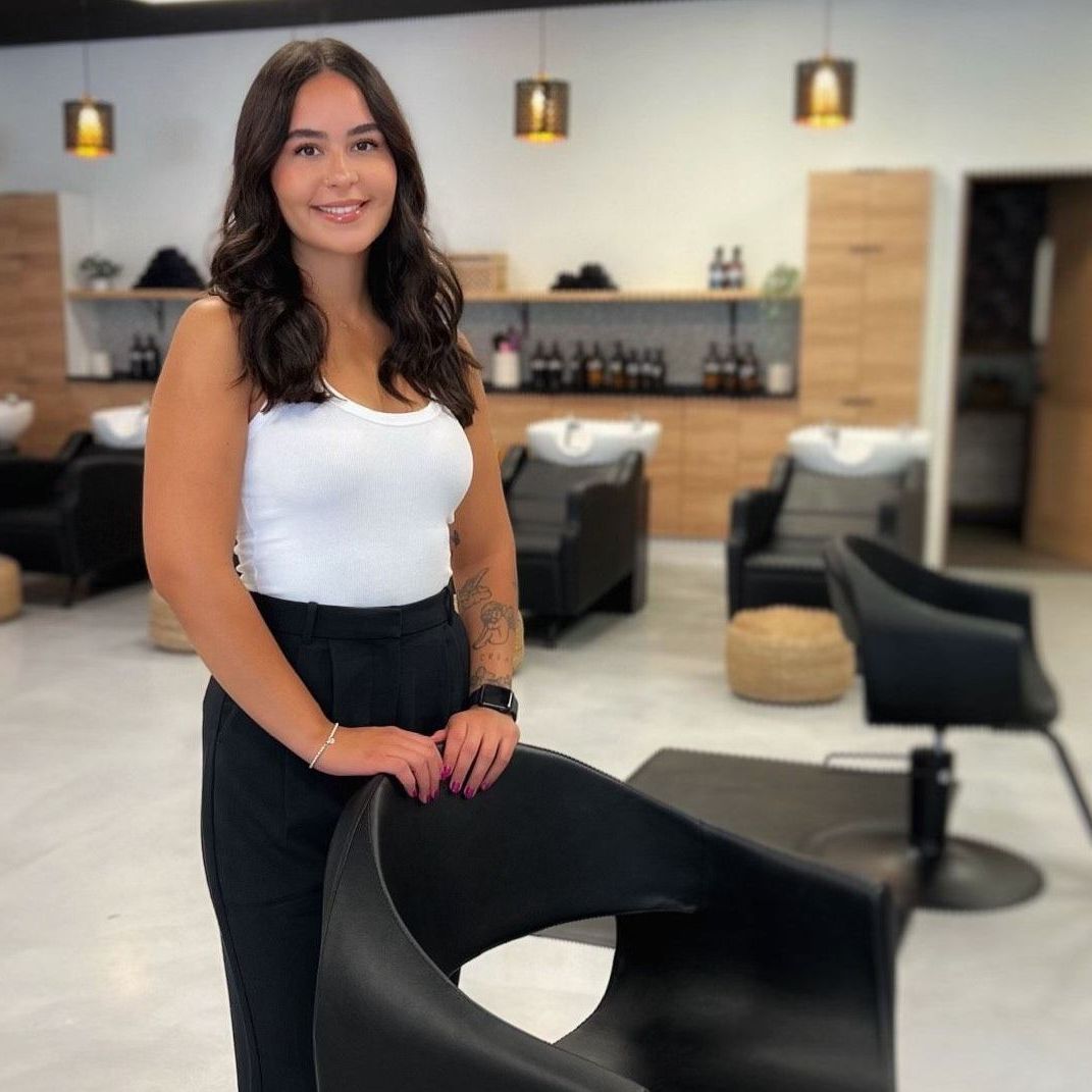 A woman standing next to a chair in a salon