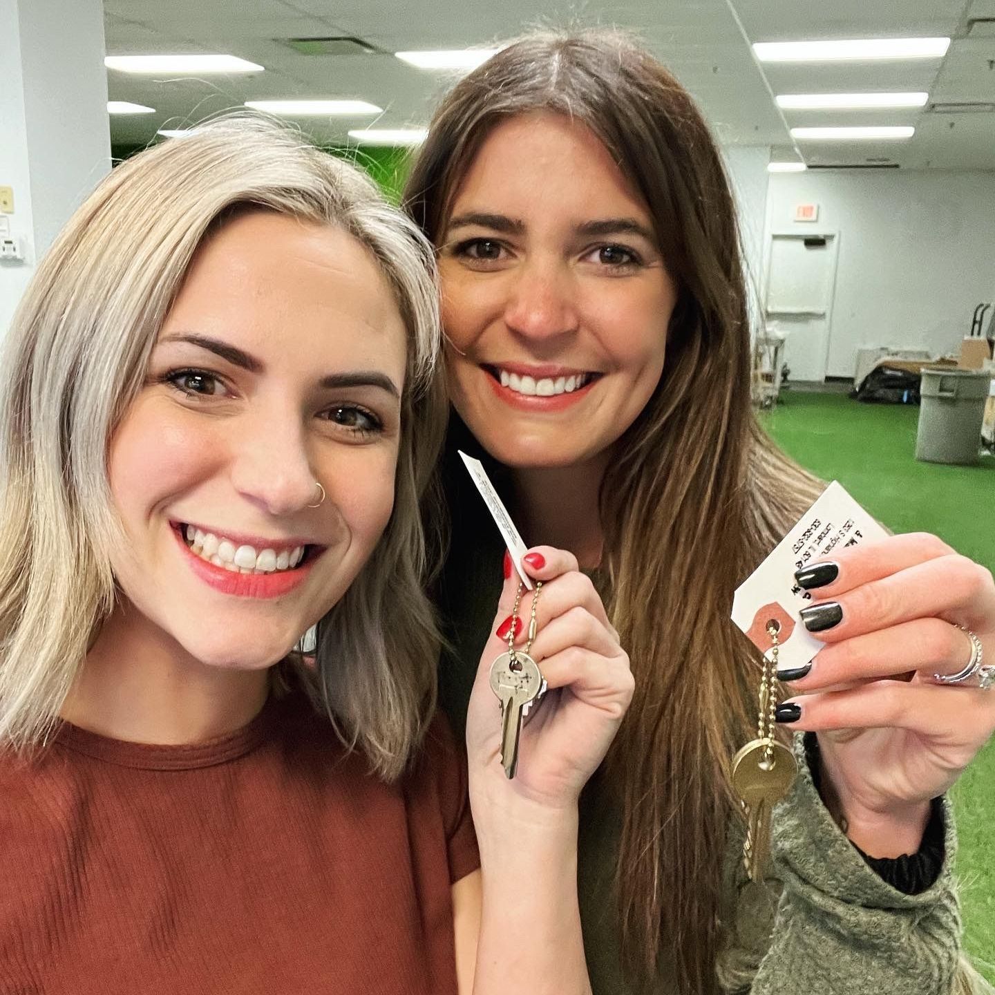 Two women are smiling and holding keys in their hands