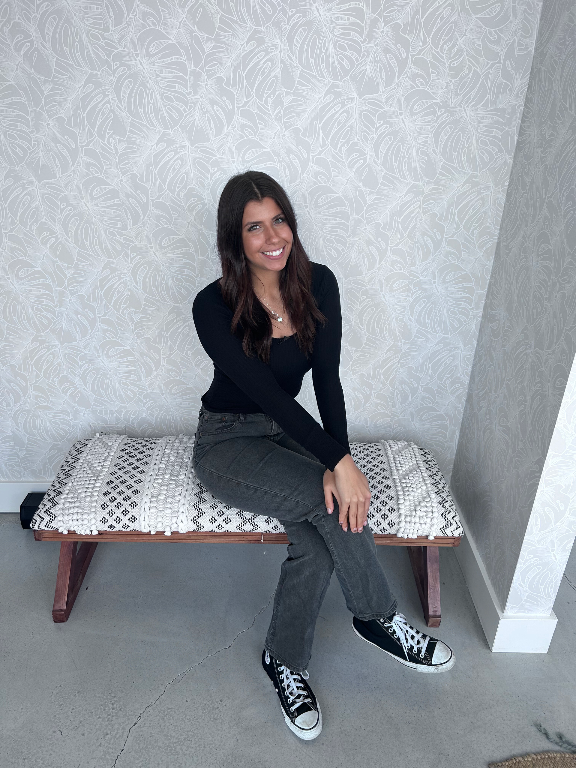 A woman is sitting on a bench with her legs crossed