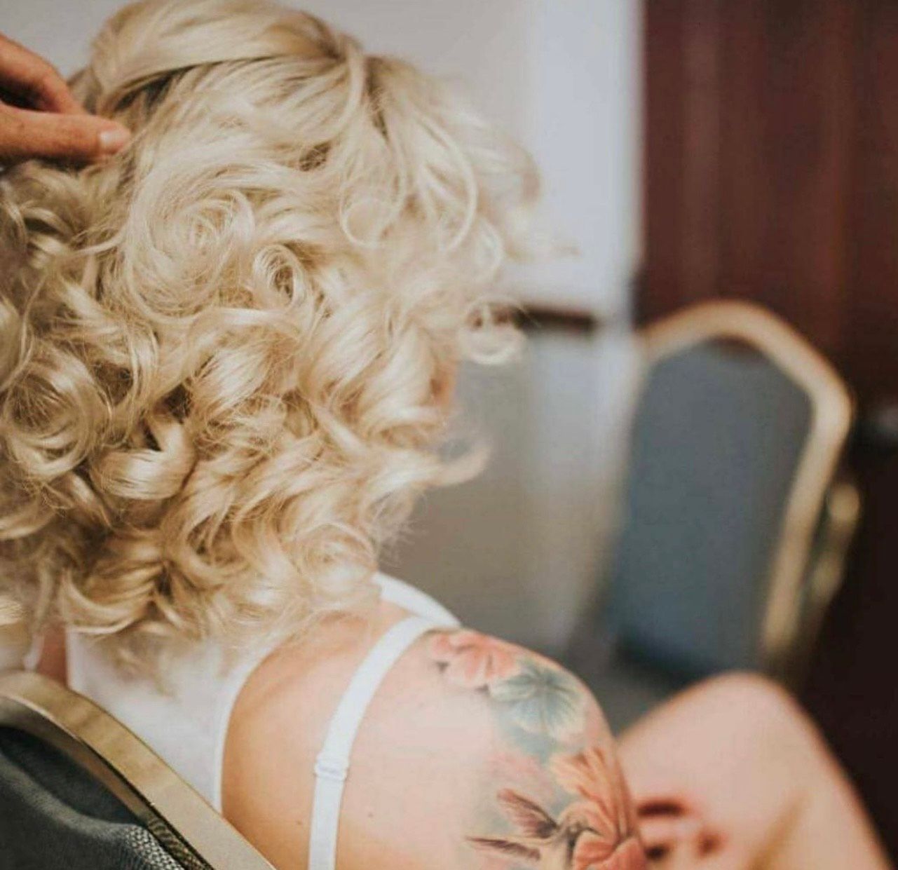 A woman with a tattoo on her shoulder is getting her hair done.