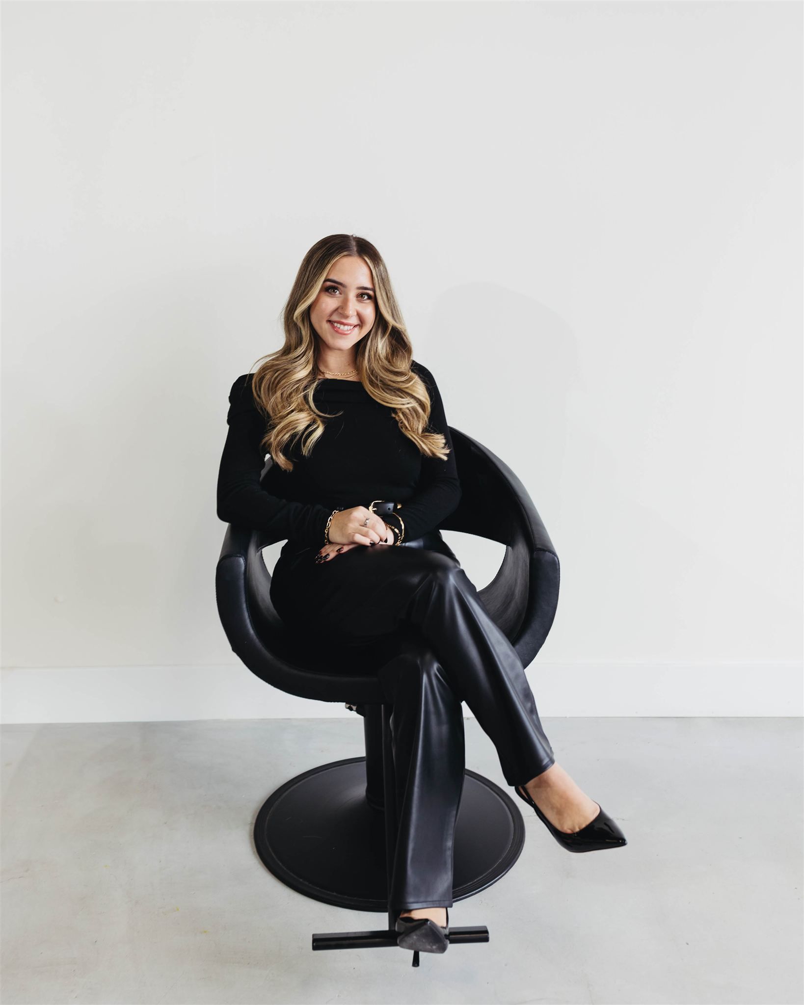 A woman is sitting in a black chair in a salon
