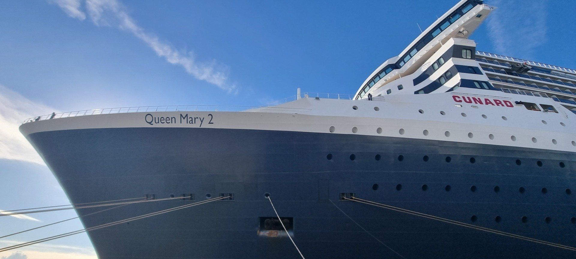 A large cruise ship called queen mary 2 is docked in a harbor.