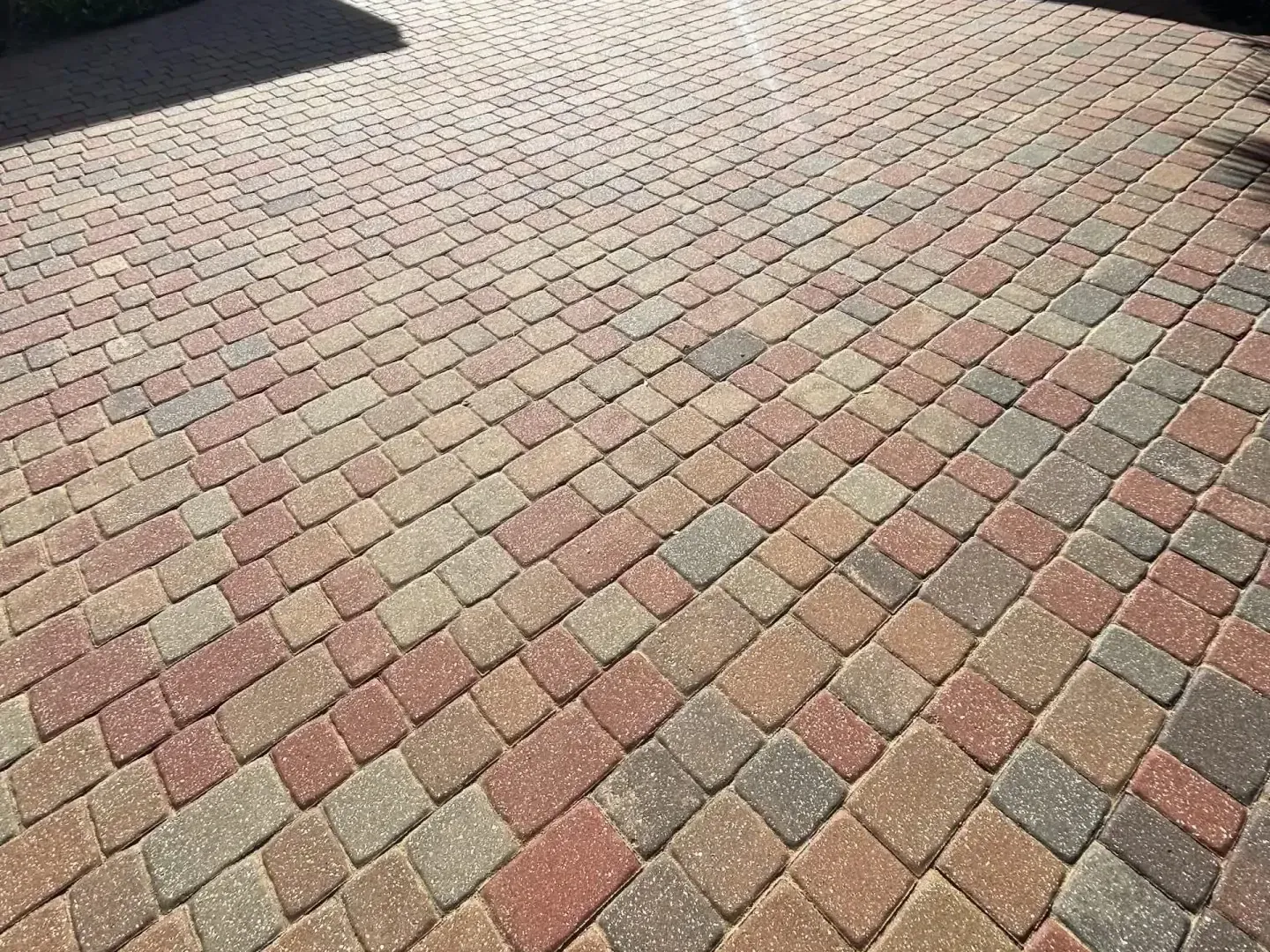 Brick paving in various shades of red and tan, arranged in a diagonal pattern.