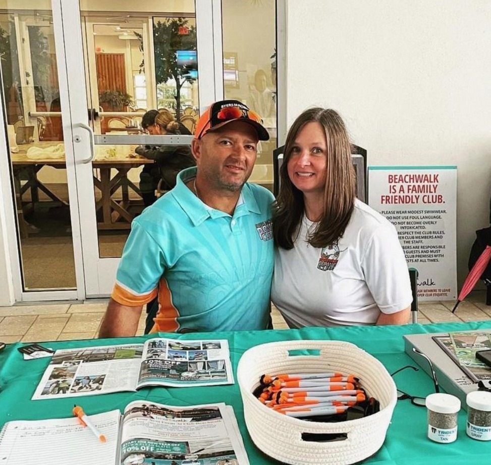 Man and woman at a promotional table, smiling. Turquoise shirt, white shirt. 