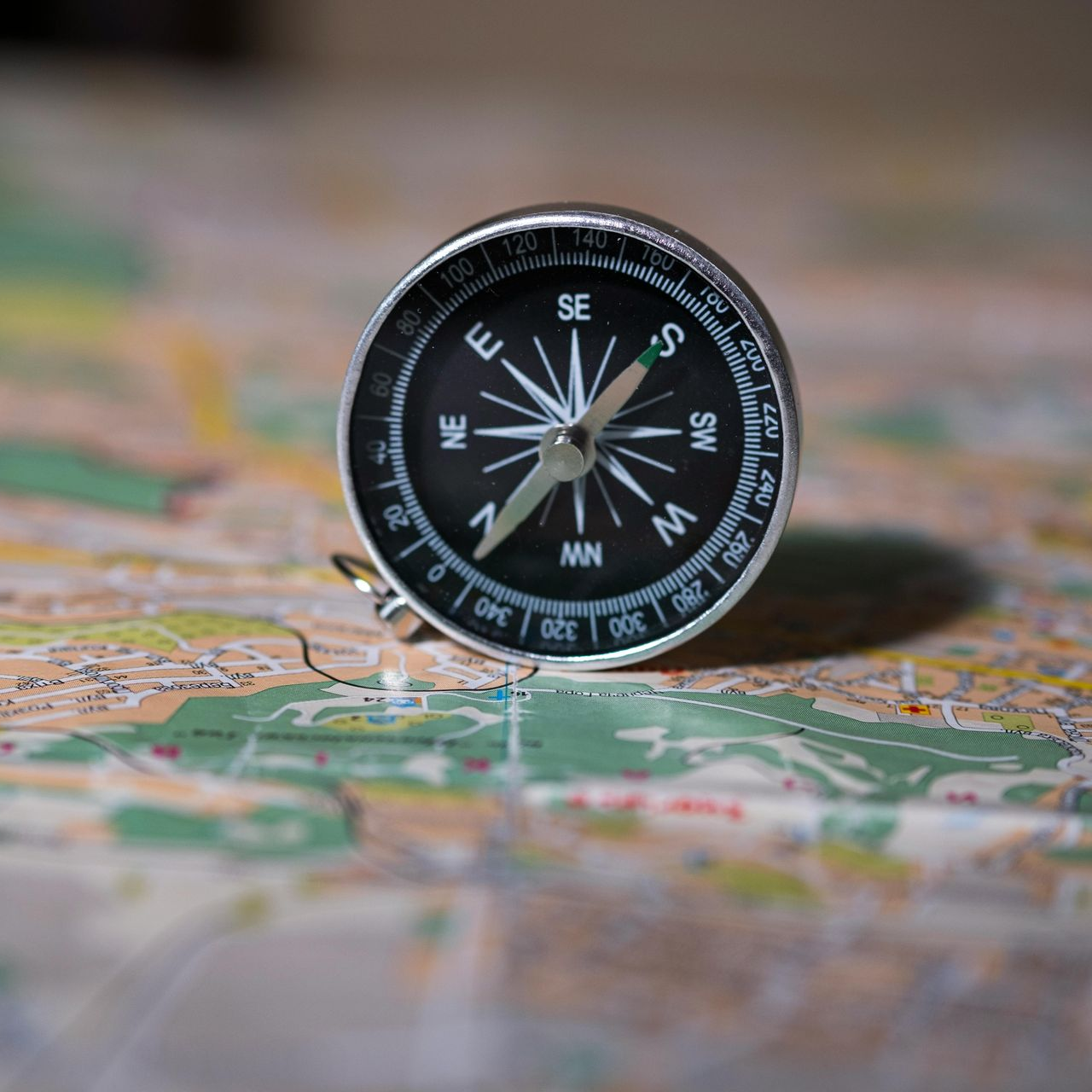 Compass on a map, showing direction. The compass is black and silver.