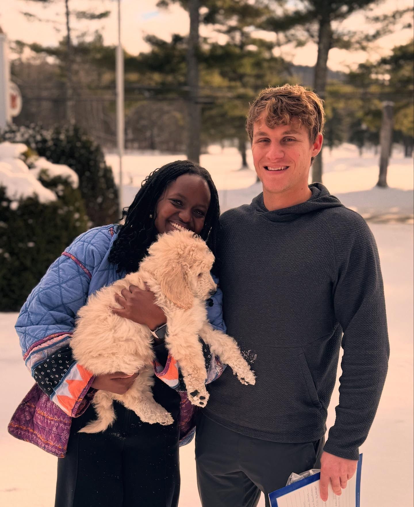 Two people holding their new standard poodle puppy