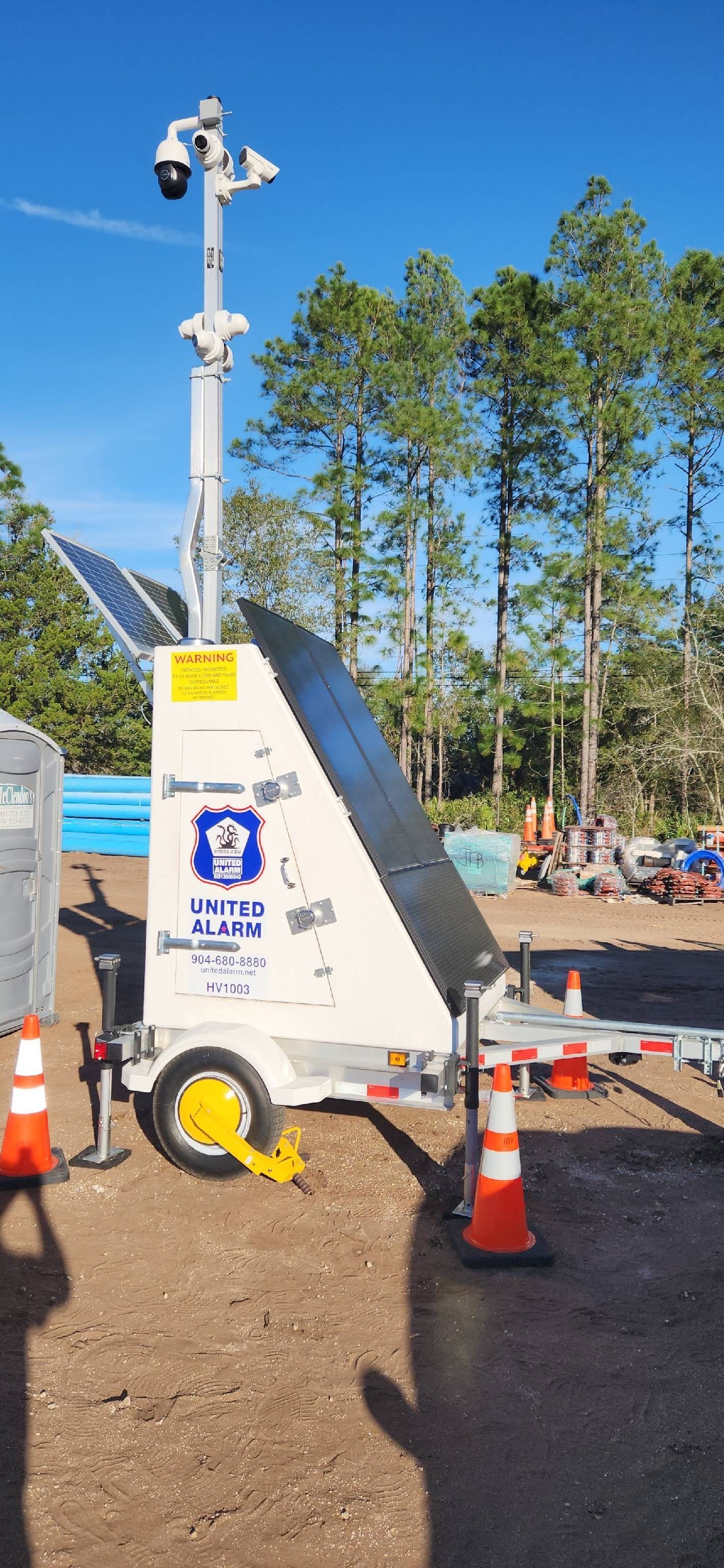 Mobile weather station on a trailer with sensors, cones, and workers in the background outdoors