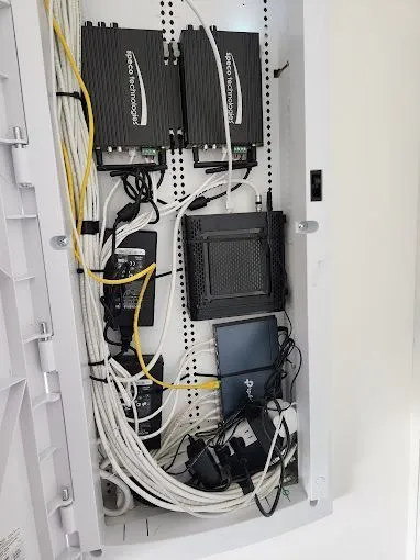 Open electrical junction box with exposed wires mounted on a wooden ceiling panel