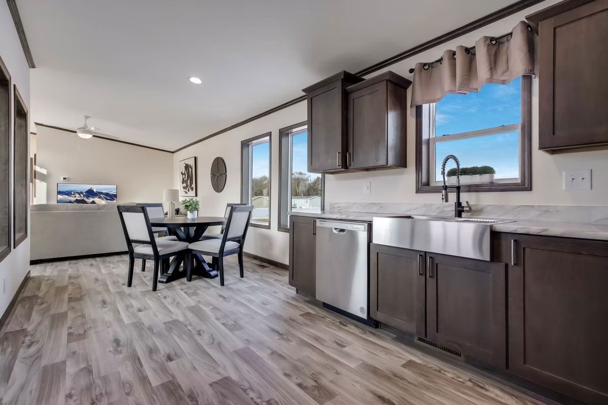 Open-concept kitchen and dining area with dark cabinets, stainless steel appliances, and a round table.