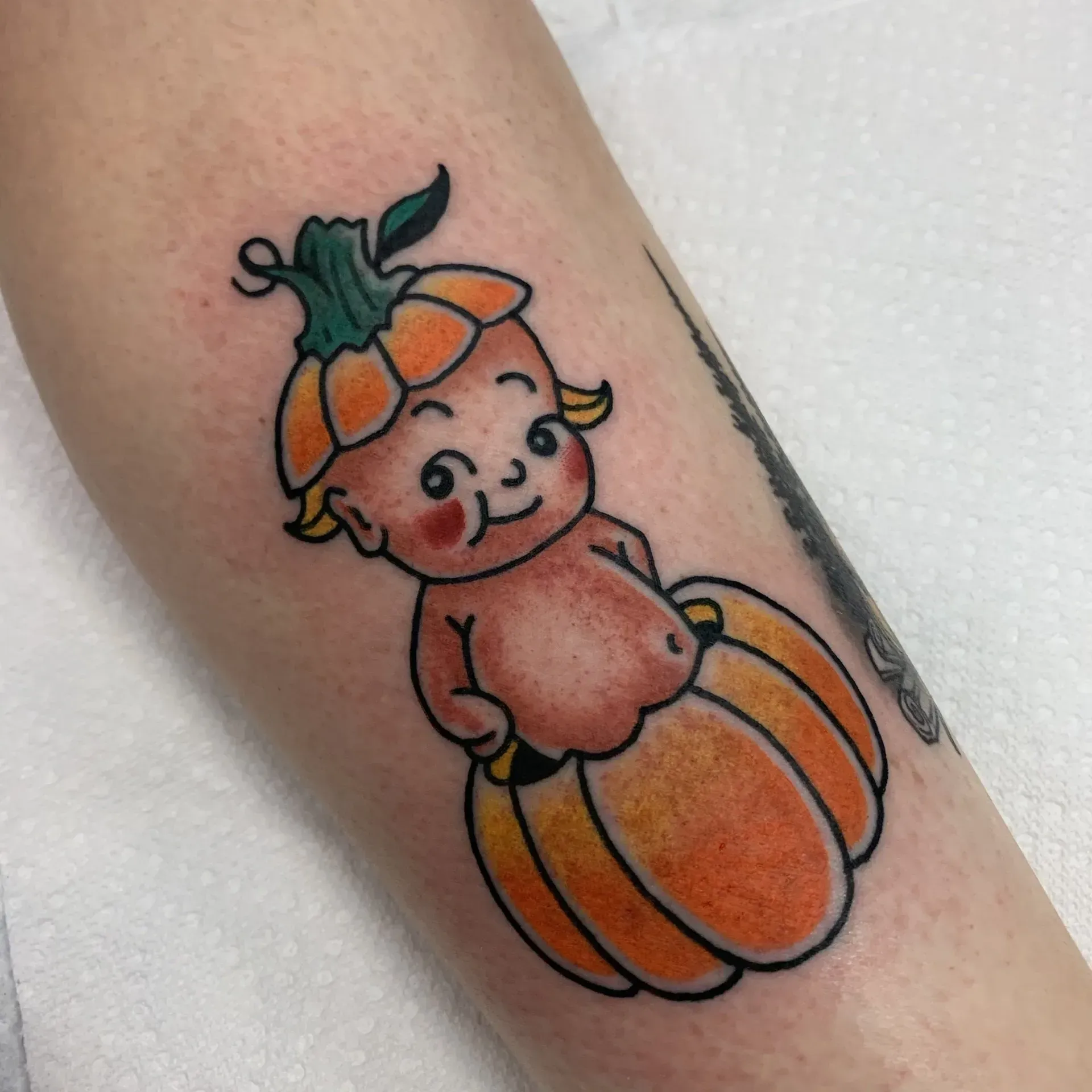 A tattoo of a baby in a pumpkin on a person 's arm